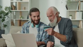 Young adult assists elderly man with online shopping via app, using bank card for secure payment, enhancing digital literacy, cross-generational tech education, bridging digital divide - Powered by Shutterstock - Get 15% off with code: PIKWIZARD15