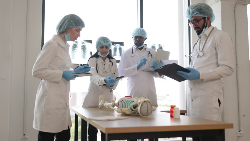 Indian woman medical teacher teaching anatomy to university students or young doctors. Arabian and African men, Caucasian woman standing near table, working with human skeleton model with body organs. - Powered by Shutterstock - Get 15% off with code: PIKWIZARD15