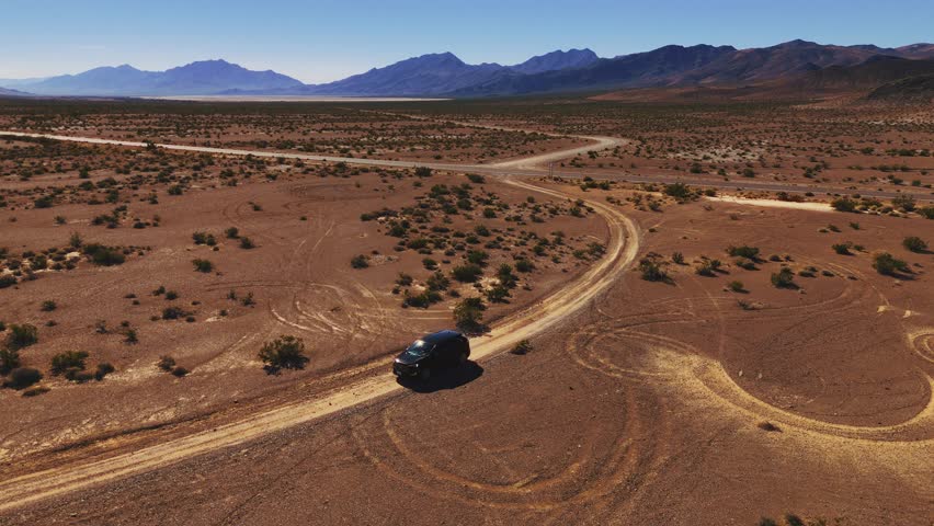 Car driving on desert dirt road off-road in Nevada close to Death Valley. Dry hot Wild West America landscape. Aerial drone