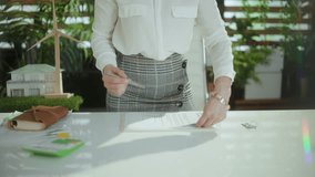 Eco real estate business. Closeup on elegant woman realtor in modern green office in white blouse with calculator and document. - Powered by Shutterstock - Get 15% off with code: PIKWIZARD15