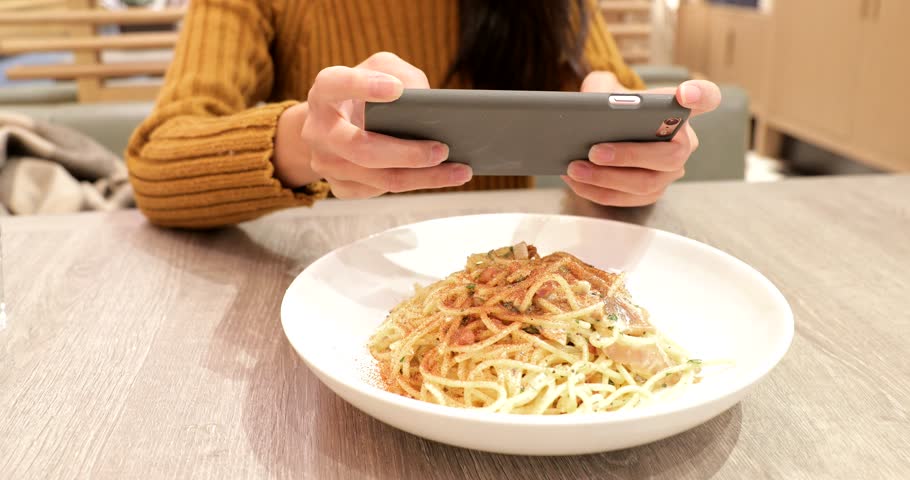 Woman taking photo on dishes in restaurant