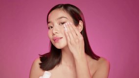 Young Asian girl applying cosmetic lotion on her skin against pink background - Powered by Shutterstock - Get 15% off with code: PIKWIZARD15