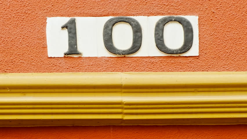 Number 100 (one hundred) affixed to the exterior of a building, with an elegant, vintage and traditional appearance

