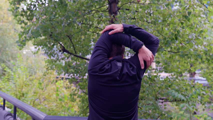 Active and fit male runner in warm-up stretch for running or cardio exercise.