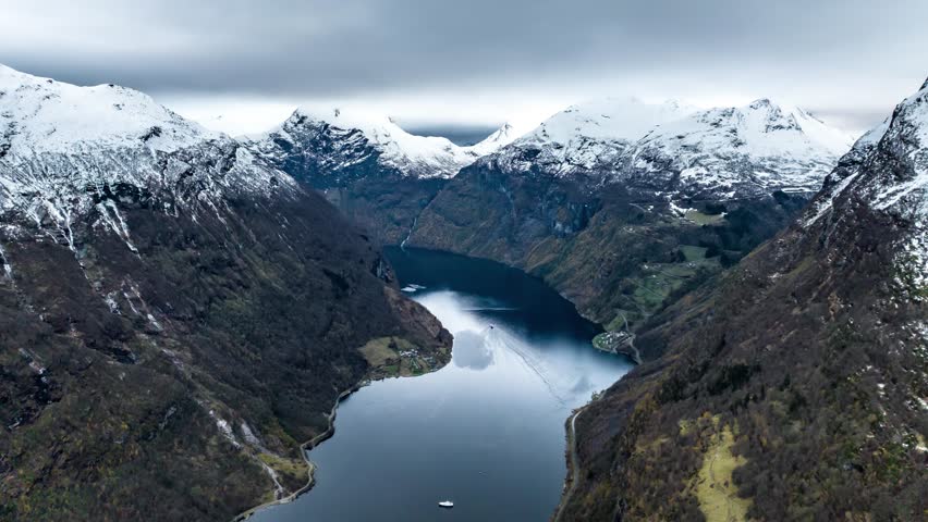 aerial hyper lapse time lapse of a boat ferry sailing in geiranger fjord between mountains covered with snow in norway Royalty-Free Stock Footage #3422983733