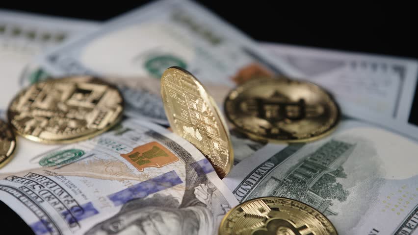 Close-up of metallic shiny bitcoin cryptocurrency coins. Crypto Bitcoin, virtual money and hundred dollar bills. Exchange dollar for bitcoin. Golden Bitcoin.