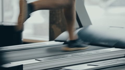 Male legs running on a treadmill in gym