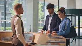 Hotel guests paying contactless with smartphone. Friendly receptionist helping joyful clients to check in. Smiling businesspeople travel making payment in contemporary lobby. Business trip concept. - Powered by Shutterstock - Get 15% off with code: PIKWIZARD15
