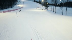 A person is skiing down a ski slope, scen from the end of the trail, drone shot.