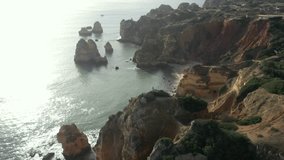 Aerial video of a woman standing on cliffs on the coastline in Carvoeiro, Algarve, Portugal