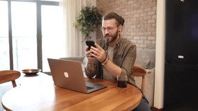 Happy man enjoying coffee break and using smartphone