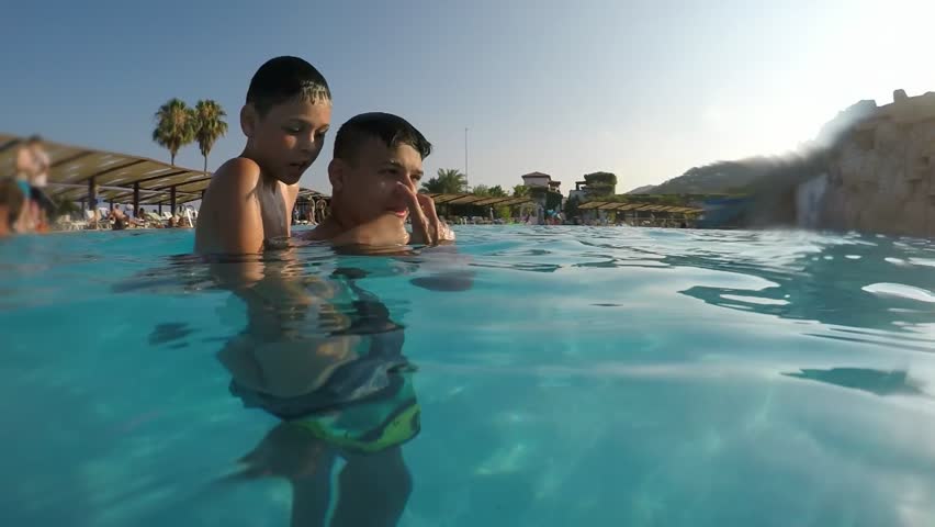 A funny view of two btothers. One of them stands on the shoulders of the other in the Mediterranean Sea and jumps like a bomb in slo-mo