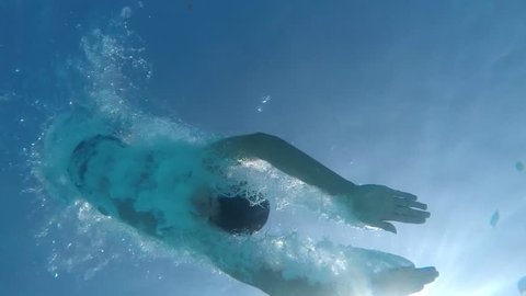 A stunning view of a young man doing a swallow dive on a Turkish resort in the Mediterranean sea. He is shot from underwater in slow motion.