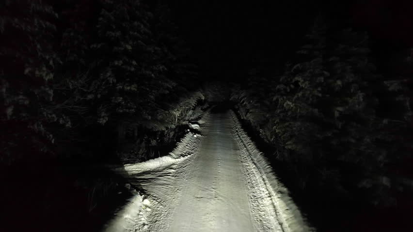 Aerial view of a modern EV car driving in middle of snowy forest, night in Lapland