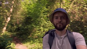Traveler gesturing hand at camera during video blog. Influencer Tourist with backpack Hiking on Adventure Trip in Natural Woods Landscape. POV video 