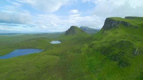 AERIAL: Beautiful landscape of The Quiraing with jagged peaks and blue lakes. Stunning green hills and valley with scenic walking paths at the northern part of famous Trotternish Ridge on Isle of Skye