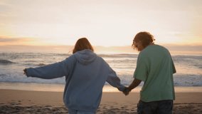 Love teenagers running sandy beach evening back view. Two young lovers walking dog holding hands at summer oceanside. Carefree boyfriend girlfriend couple enjoying sea breeze together at sunset nature - Powered by Shutterstock - Get 15% off with code: PIKWIZARD15
