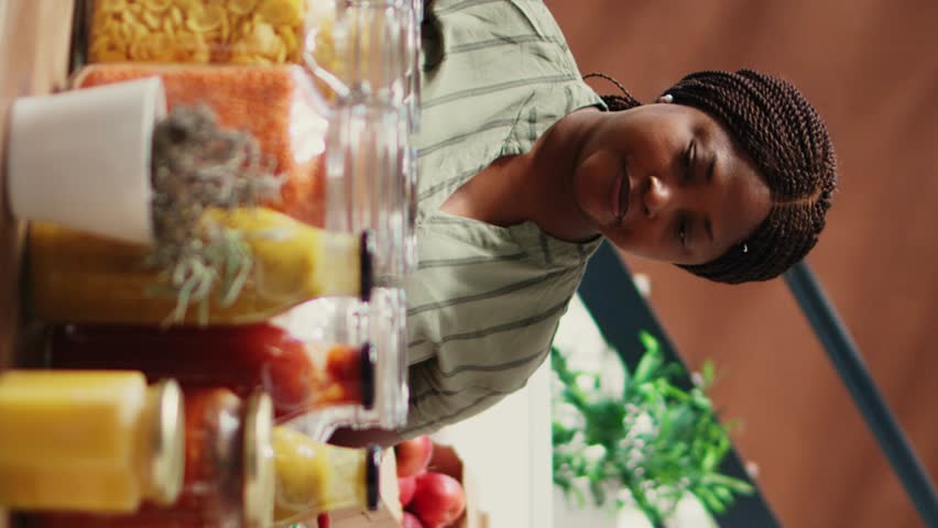 Vertical Video Vendor showing homemade sauces and dressings to buyer, promoting vegan nutrition and healthy lifestyle. Retailer presenting natural bulk items at local grocery store. Handheld shot.