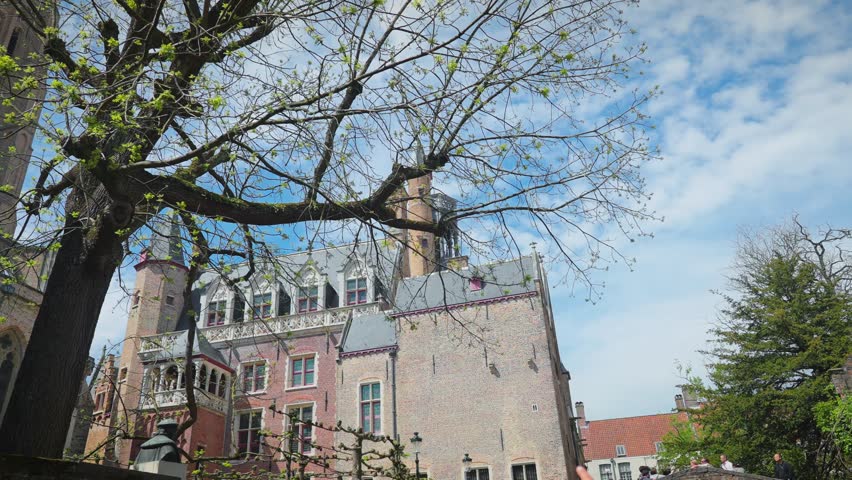 Low angle shot of a medieval historic tall church of our lady on a sunny bright day with the clear blue sky and clouds in the background in Brugge, Belgium. concept of travel and tourism