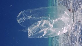 Vertical footage, Plastic bag and other garbage floats on polluted surface of Ocean, fishes swims nearby, Slow motion. Plastic bag and other debris drifting in fattty layer on surface of water 