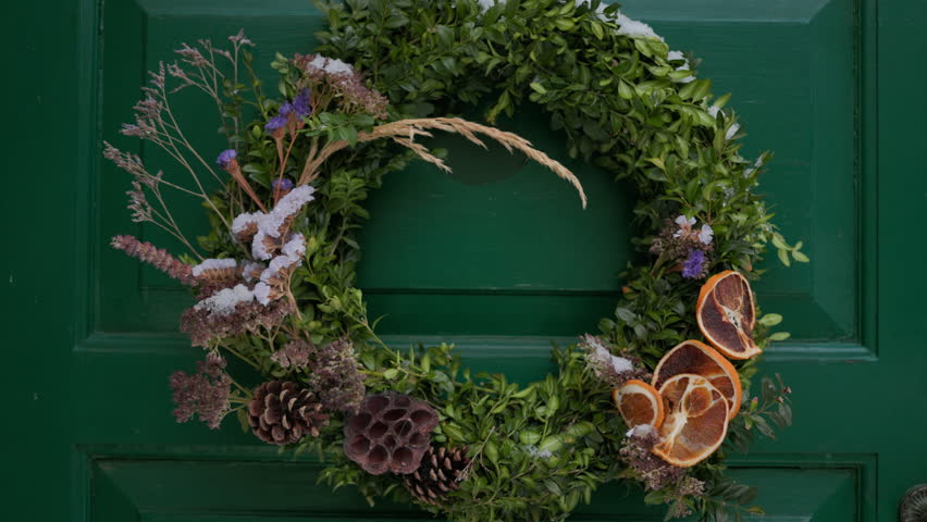 Beautiful entrance to scandinavian style house with wooden door and christmas wreath. Homemade diy xmas decoration. Winter city doors and landscape. Inspiring winter ornaments and nordic lifestyle