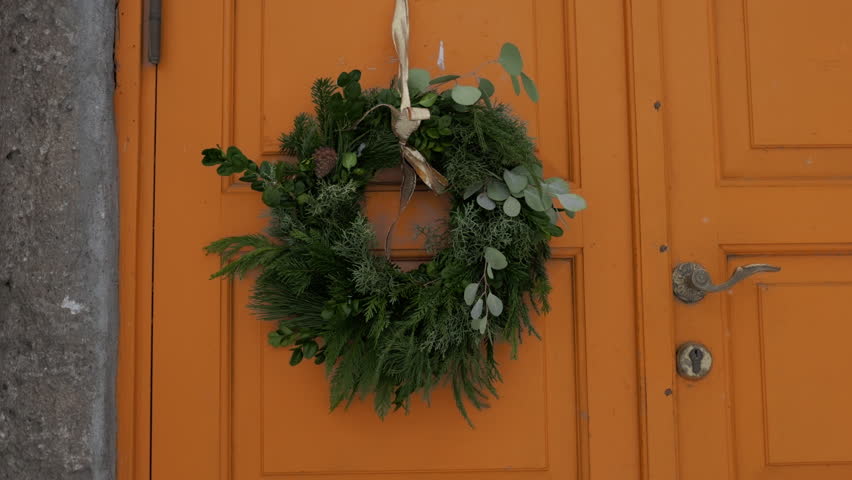 Beautiful entrance to scandinavian style house with wooden door and christmas wreath. Homemade diy xmas decoration. Winter city doors and landscape. Inspiring winter ornaments and nordic lifestyle