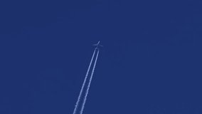 The journey begins, plane flies high in the sky, leaving a white trail. Jet airplane flying overhead in clear blue sky and leaving nice contrail. Plane smoothly as it flies through the sky