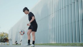 Young woman in sportswear juggling a soccer ball with her legs outdoors on city street in front of modern urban building. Full length shot, copy space - Powered by Shutterstock - Get 15% off with code: PIKWIZARD15
