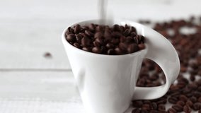 Roasted coffee beans fall into a white cup. Close-up. - Powered by Shutterstock - Get 15% off with code: PIKWIZARD15