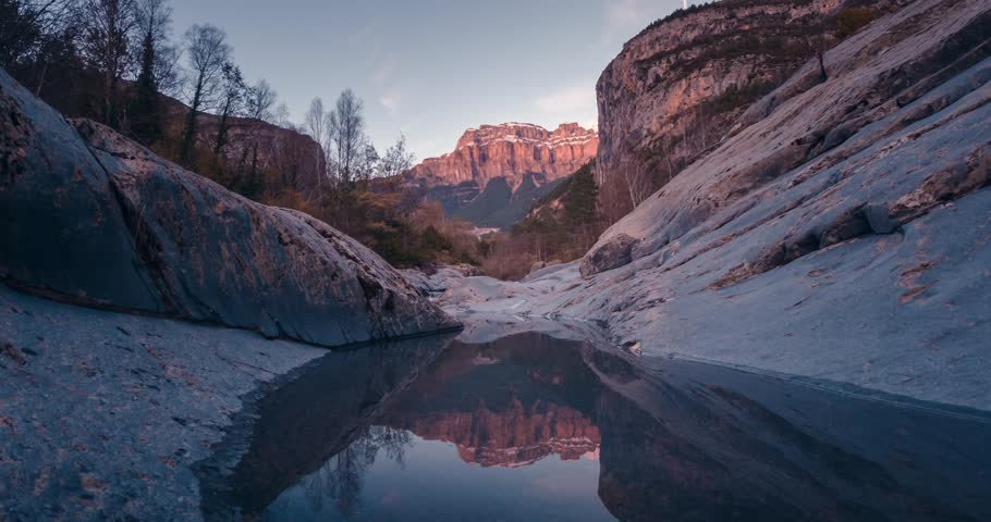 Small lake reflection in Ordesa National park Mondarruego mountain catching last sunrays during sunset timelapse in fall autumn season