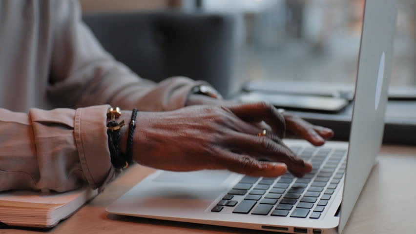 African American man typing text on laptop. Works in the office. Close up. Sitting at the table