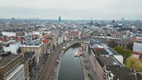 The drone is flying forward above Rokin canal and street with an overlook of the city centre on a cloudy day in Amsterdam The Netherlands Aerial Footage 4K