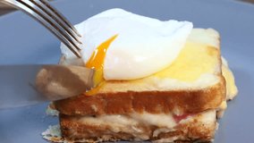 Close up view of Poached egg spreads over the sandwich in slow motion. Croque madame, grilled sandwiches with sliced ham, melted cheese, dijon mustard and poached egg in bechamel sauce. - Powered by Shutterstock - Get 15% off with code: PIKWIZARD15