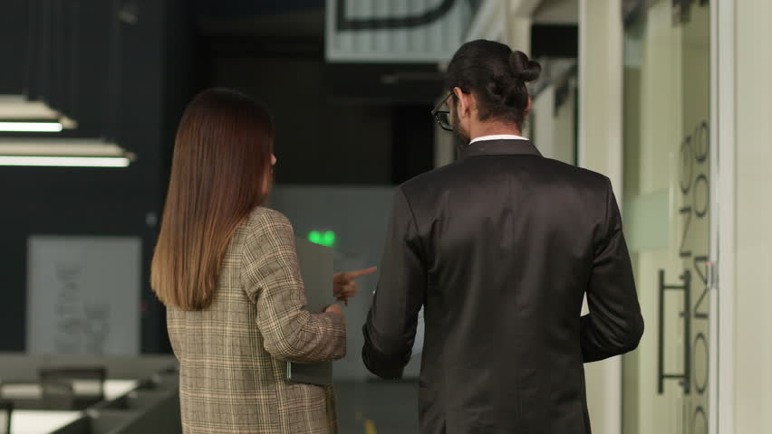 Back view from behind diverse multiracial colleagues business people walking in office hallway corridor lobby discussing documents papers contract new startup project woman and man multiethnic talking - Powered by Shutterstock - Get 15% off with code: PIKWIZARD15