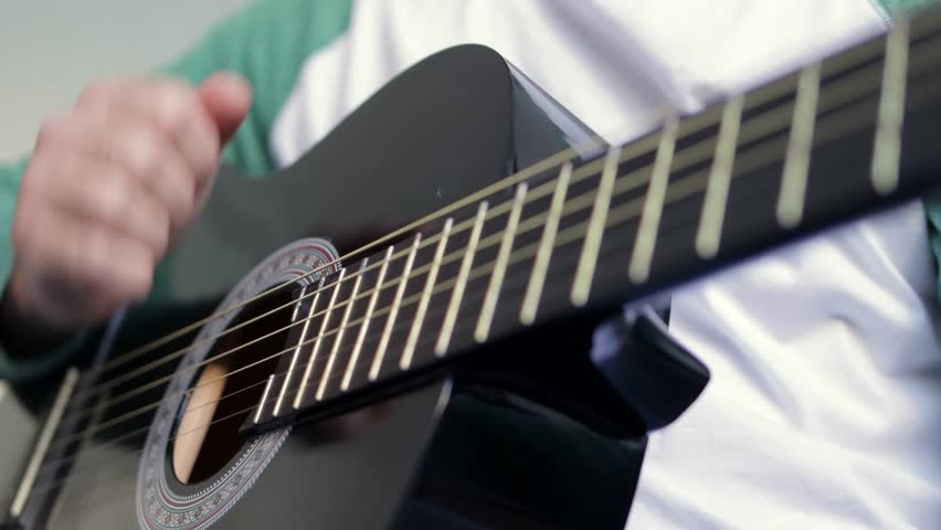 Close-up of a mans hands playing a classical guitar. Guitarist plays guitar in the house.
