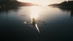 Cinematic drone shot of a crew of two women, blue water rowing team, early morning, training at sunrise. Aerial view of canoeing athletes rowing synchronously in a sporty two-seater rowing boat - Powered by Shutterstock - Get 15% off with code: PIKWIZARD15
