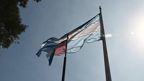 video of the Argentine national flag next to the official flag of Cordoba flying in the blue sky