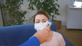 Health care. Doctor measures the temperature of patient wearing medical mask while sitting at home. Patient wearing mask with symptoms of high fever. Medical worker taking temperature - Powered by Shutterstock - Get 15% off with code: PIKWIZARD15