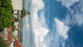 Vertical video - Timelapse of white puffy clouds forming in the blue sky over the suburb in Bandung, Indonesia