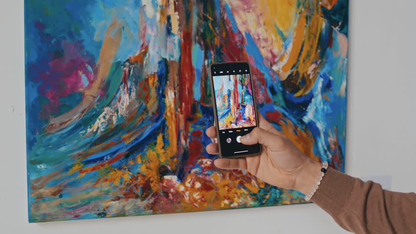 Medium close-up rear shot of hand of Middle Eastern male art museum visitor standing in front of colourful abstract painting and taking detailed photos of artwork on smartphone Royalty-Free Stock Footage #3423981395