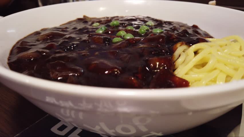 Noodles in Black Bean Sauce (Jajangmyeon or jjajangmyeon), a popular Korean Chinese chewy wheat flour dish with a thick sauce made of chunjang, diced pork, and vegetables. A catering concept. 4k24.
