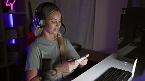 Smiling young woman with headphones using smartphone in a neon-lit gaming room at night