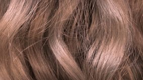 Slow motion video of human brown hair from back side. Background of healthy blonde long wavy hair close-up texture. Concept of hair care, cure, treatment, coloring, dyeing and extension.