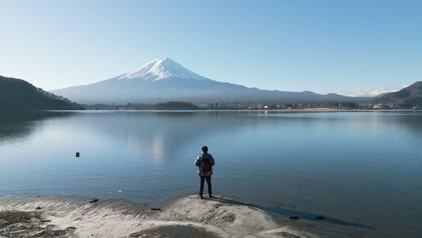 Happy man enjoy outdoor lifestyle travel Japan on winter vacaton at Lake Kawaguchiko with snowcapped Mt. Fuji in the background Royalty-Free Stock Footage #3424154935