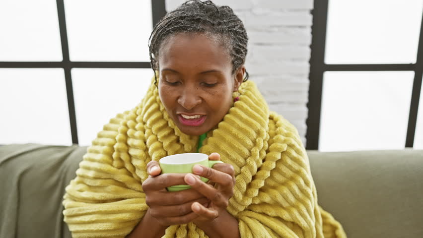 African american woman in yellow robe enjoying coffee at home