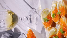 Salmon caviar in a white bowl and red caviar sandwiches with white wine. Gourmet food up close. Seafood and delicatessen. vertical video