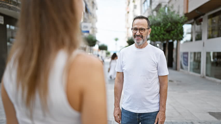 Confident father hugging his smiling daughter on a sunny street, sharing joy and happiness together