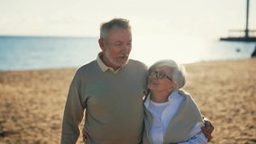 Senior couple walking on sandy ocean beach talking smiling hugging resting together. Loving wife husband family enjoying time important date. Lifelong relationships, happy marriage, care love concept. - Powered by Shutterstock - Get 15% off with code: PIKWIZARD15