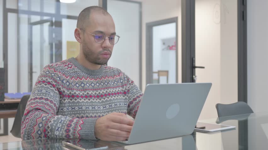 Young Hispanic Man Chatting Online on Laptop while Sitting