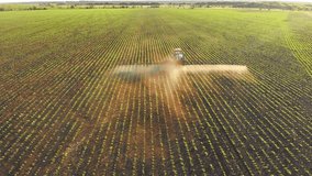 Aerial video of tractor spraying soil and young crop in springtime in field. Tractor spraying pesticides on soy field with sprayer at spring. Nozzle of the combine industry sprinklers sprayed.
